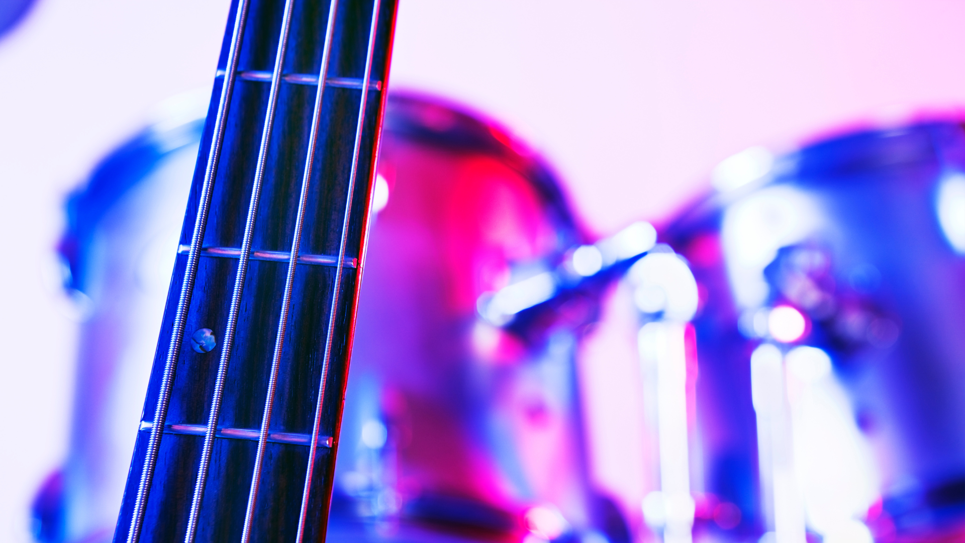 Fretboard of a bass guitar on a stage in front of a drumkit