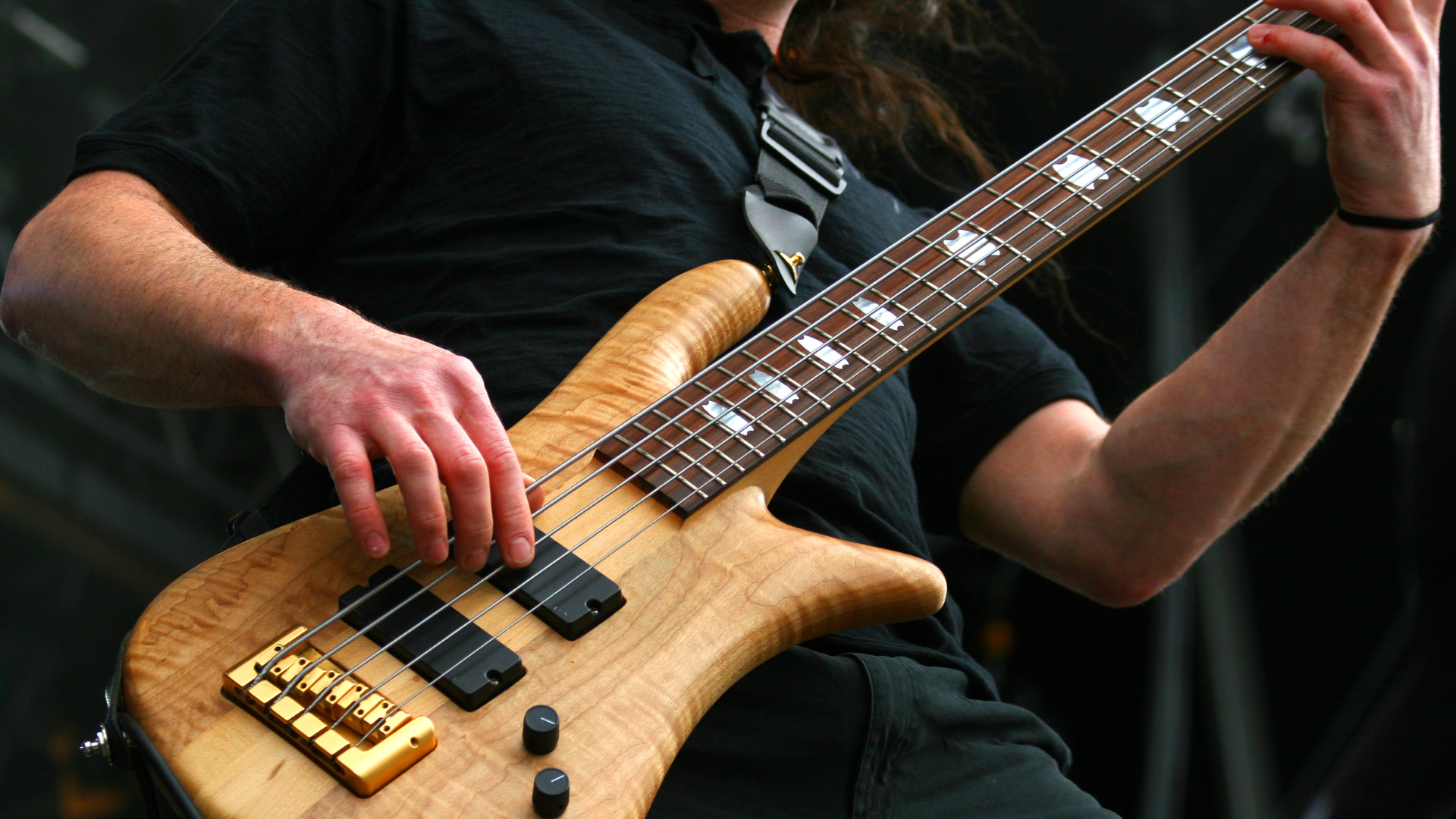 A bass player on stage with a 5 string instrument