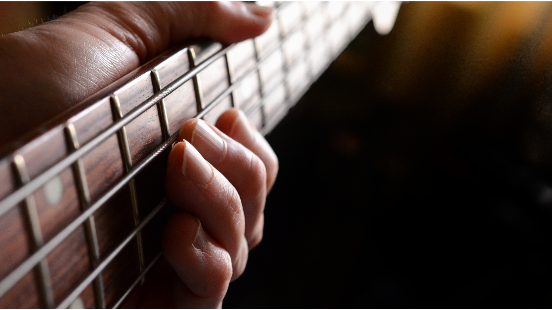 Close up photo of a bass player's hands on the fretboard